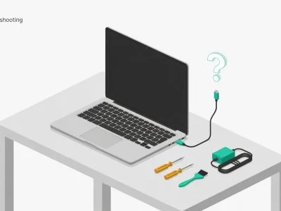A laptop on a desk with an unplugged charging cable floating nearby, alongside a small repair toolkit and power adapter