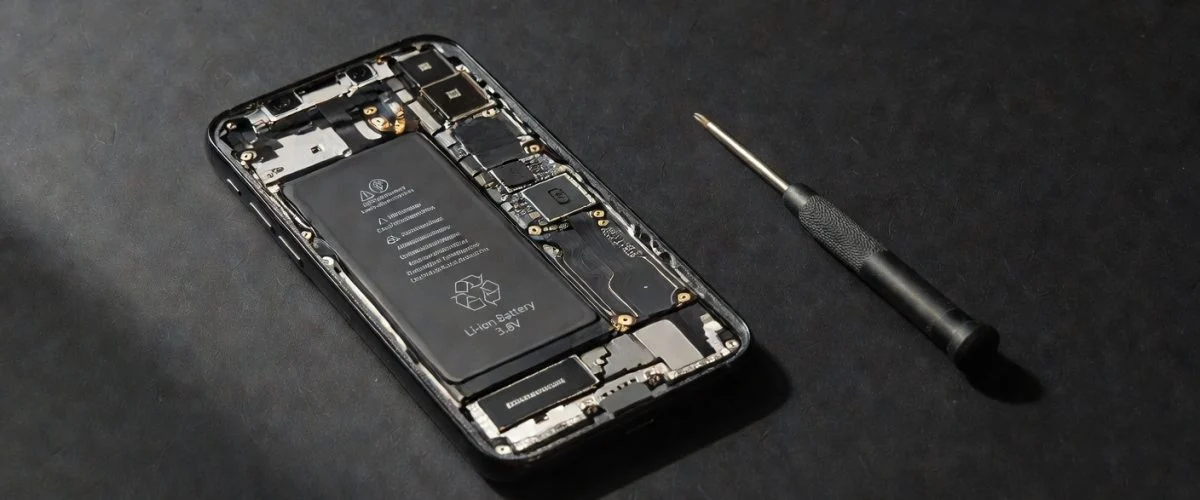 Smartphone with exposed battery and screwdriver beside it