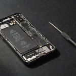 Smartphone with exposed battery and screwdriver beside it
