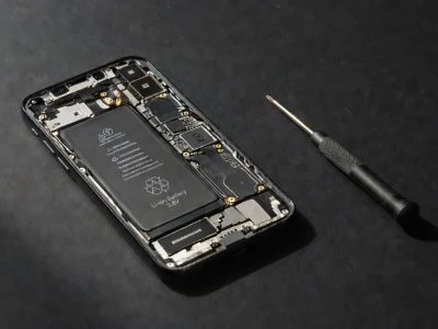 Smartphone with exposed battery and screwdriver beside it