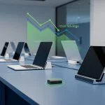 Flat design editorial illustration of a corporate IT office with laptops and tablets on charging stations, cost savings data chart overlay, and USB charge limiter device highlighted in foreground. Blue and green professional tones.