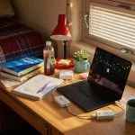 Student laptop charging setup in dorm room with USB charge limiter between power adapter and laptop computer