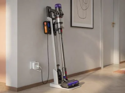 Cordless stick vacuum cleaner on a wall charging dock in a modern home hallway with a USB charge limiter attached