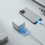 A compact white GaN USB-C charger next to a smartphone charging on a clean desk