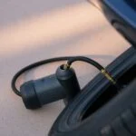 Handheld rechargeable tire inflator connected to a car tire valve on a driveway