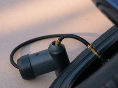 Handheld rechargeable tire inflator connected to a car tire valve on a driveway